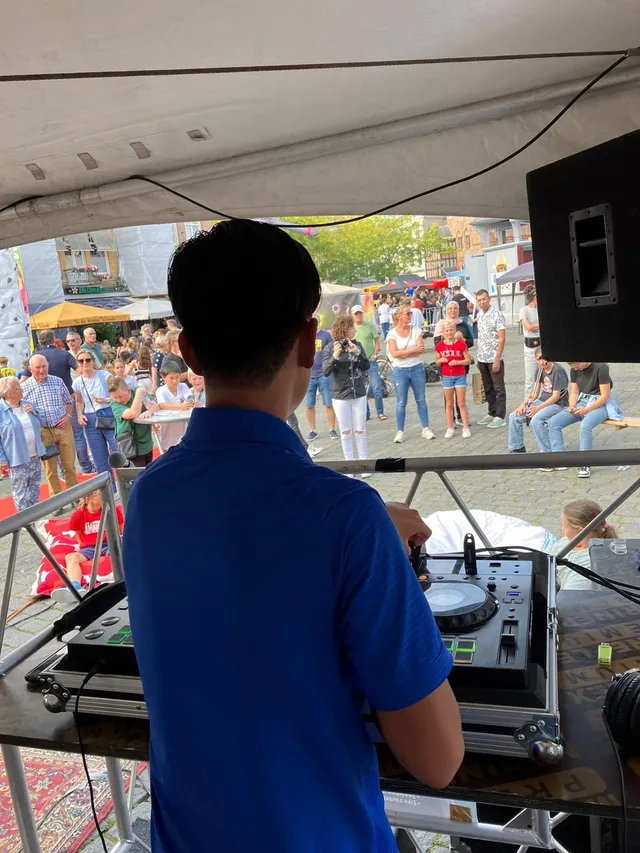 Uitzicht vanaf de booth over een druk plein tijdens een zomers festival.